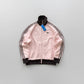 Pink Adidas jacket with black stripes on a wooden floor