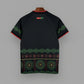 Black shirt with green and red patterns on a hanger against a grid background