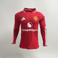 A red long-sleeve Manchester United soccer jersey displayed on a black mannequin torso. The jersey features a subtle textured pattern, white Adidas logo on the right chest, Manchester United crest on the left chest, and a white Snapdragon sponsor logo across the center.