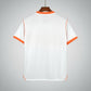 White shirt with orange accents on a hanger against a black metal grid background