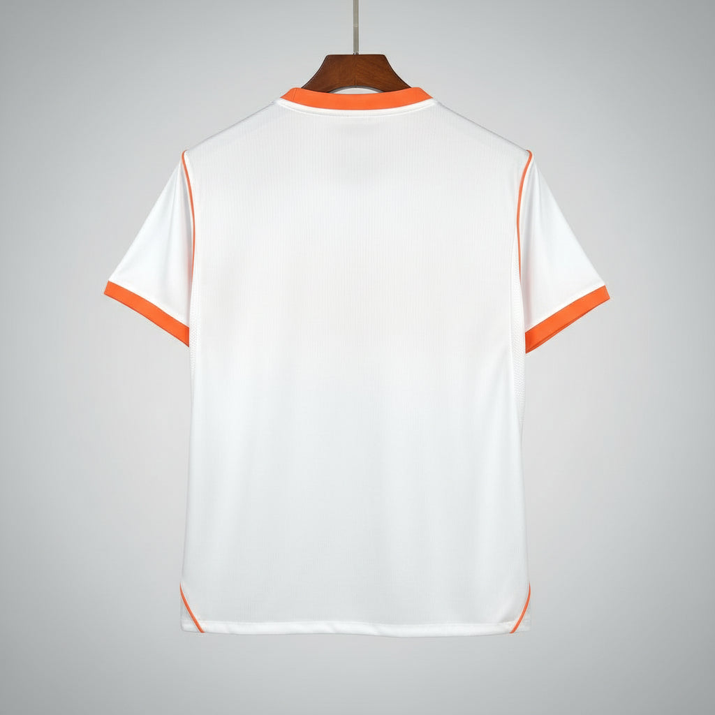 White shirt with orange accents on a hanger against a black metal grid background